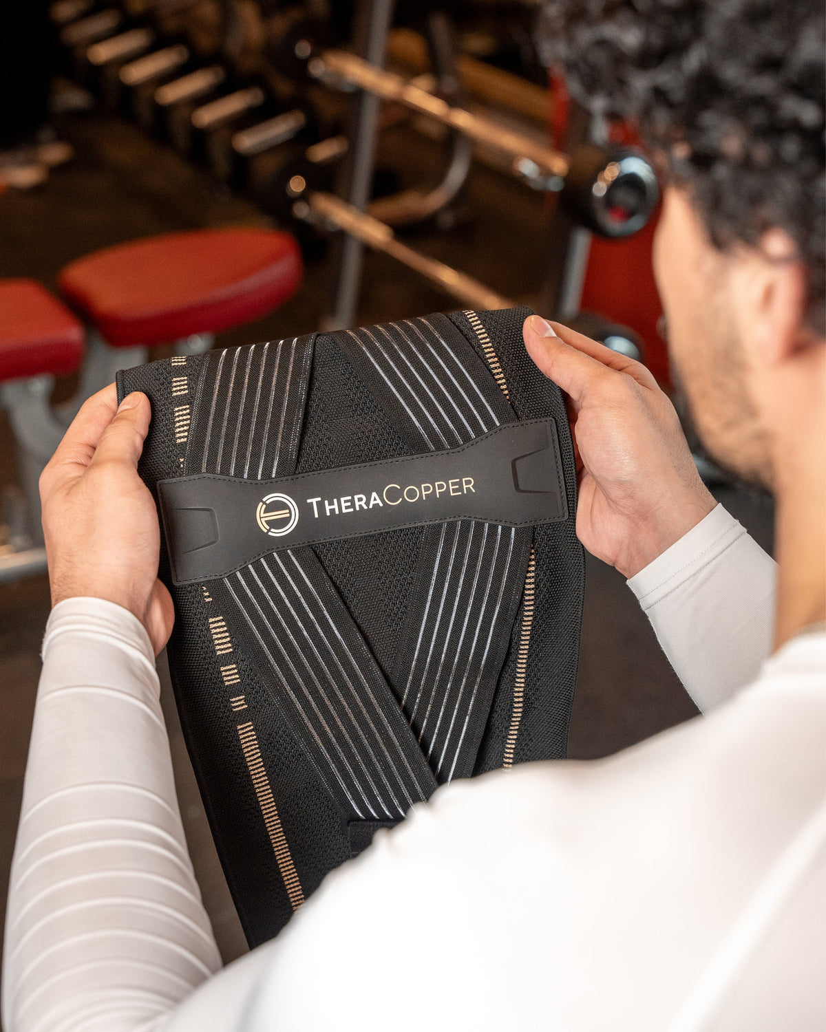 Man holding the TheraCopper lower back brace, showing the inside