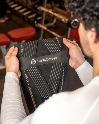 Man holding the TheraCopper lower back brace, showing the inside
