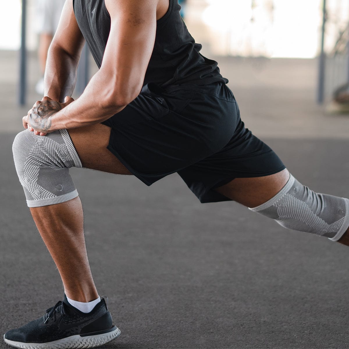 Man stretching outdoors wearing MagnetRX magnetic knee compression sleeves