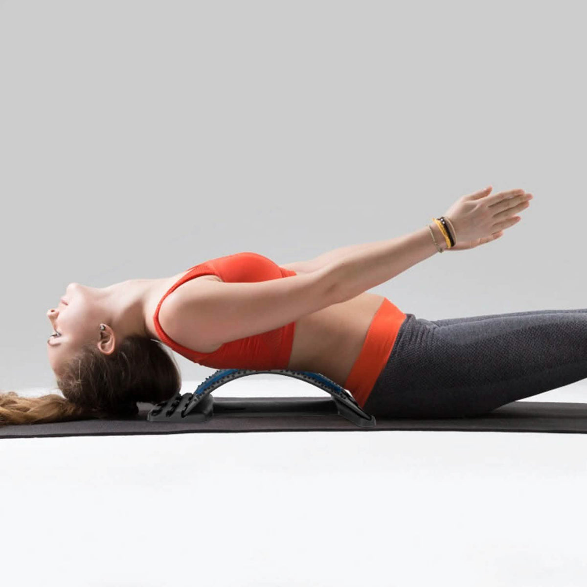 Woman lying back on the lumbar stretcher on a yoga mat