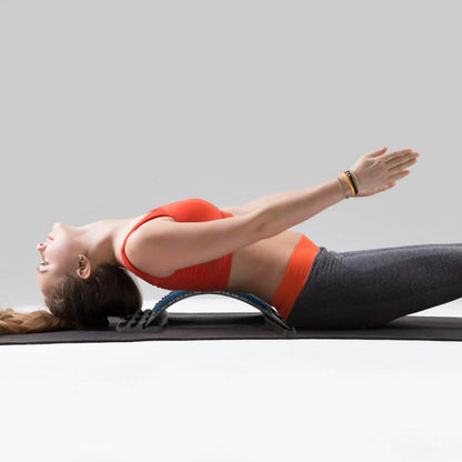 Woman lying back on the lumbar stretcher on a yoga mat